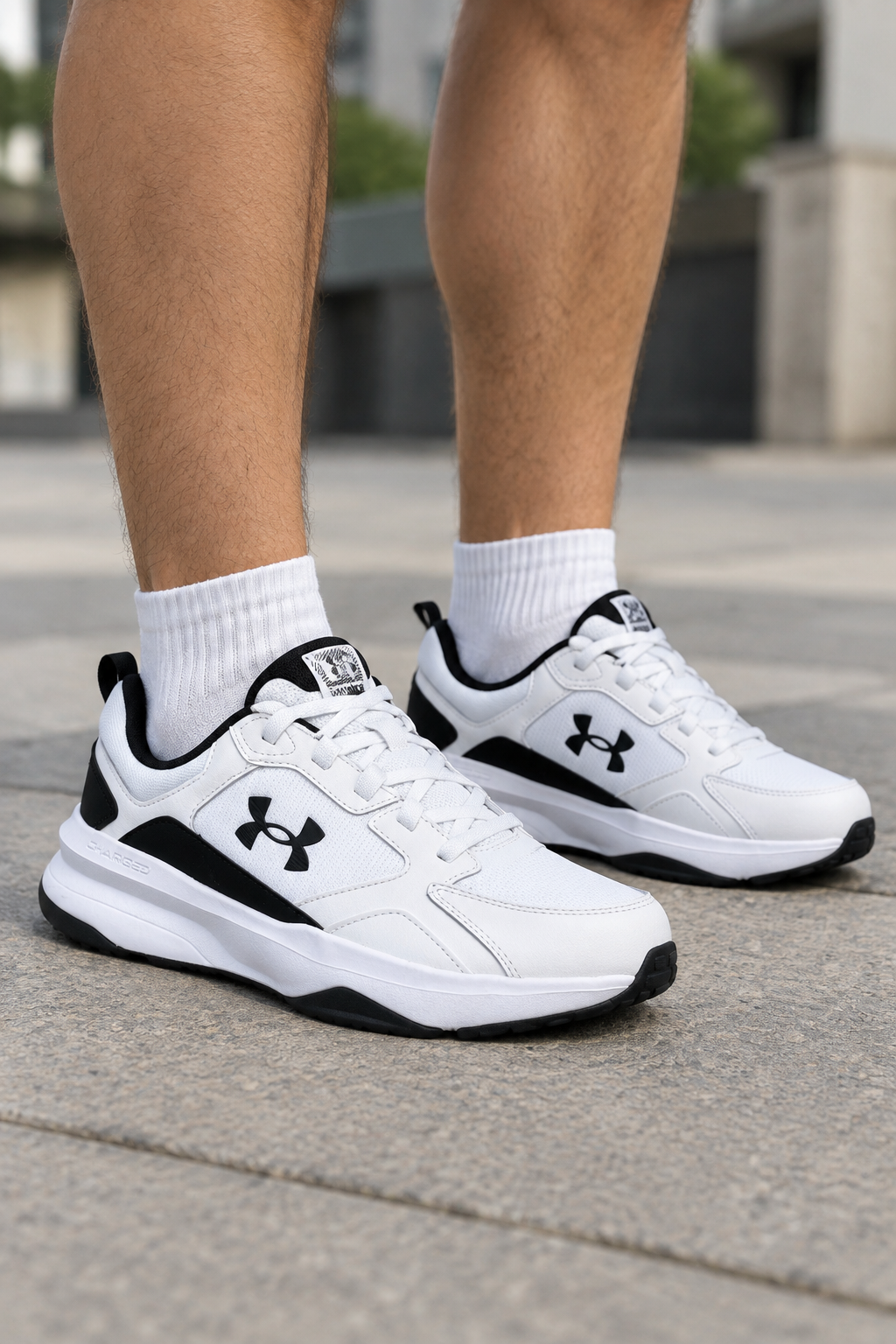 Fehér-fekete Under Armour Charged Edge cipőpár férfilábon, 3/4-es nézet